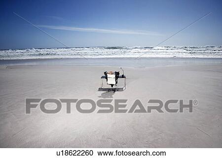 Senior business man sitting at office desk on beach, elevated view, back view View Large Photo Image Stock Image - Senior business man sitting at office desk on beach, elevated view, back view. Fotosearch