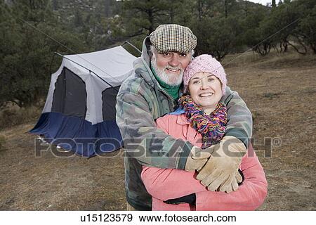 Stock Photo - Senior couple embracing in front of tent, portrait. Fotosearch