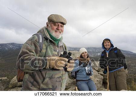 Senior man holding binoculars in mountains View Large Photo Image Stock Image - Senior man holding binoculars in mountains. Fotosearch
