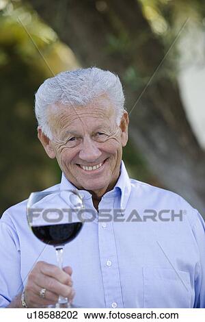 Senior man holding glass of wine, smiling View Large Photo Image Stock Image - Senior man holding glass of wine, smiling. Fotosearch