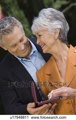 Senior man with senior woman holding pearl necklace View Large Photo Image Stock Image - Senior man with senior woman holding pearl necklace. Fotosearch
