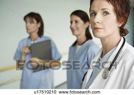 Serious Physician with Nurses in hospital corridor, focus on physician, portrait View Large Photo Image Stock Image - Serious Physician with Nurses in hospital corridor, focus on physician, portrait. Fotosearch