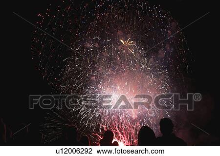 Stock Image - Shadows of spectators in front of fireworks. Fotosearch