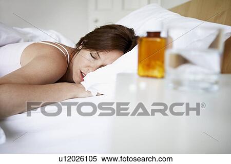 Sick woman in bed by pills on bedside table View Large Photo Image Stock Photography - Sick woman in bed by pills on bedside table. Fotosearch
