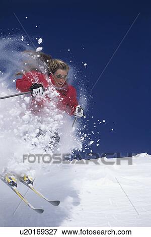 Stock Photo - Skier skiing through powdery snow on ski Slope. Fotosearch