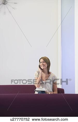 Smiling, casually dressed Businesswoman sitting on sofa, Using mobile View Large Photo Image Stock Image - Smiling, casually dressed Businesswoman sitting on sofa, Using mobile. Fotosearch