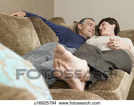 Picture - Smiling couple relaxing on sofa in living room. Fotosearch
