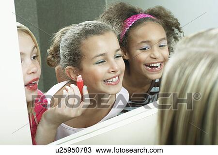 Smiling Girls looking in mirror, putting on lipstick View Large Photo Image Stock Image - Smiling Girls looking in mirror, putting on lipstick. Fotosearch