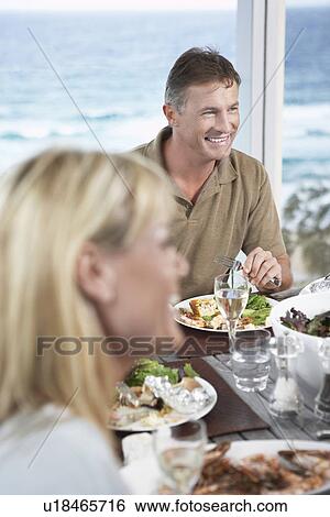 Stock Photograph - Smiling Man Eating meal outside near the sea. Fotosearch
