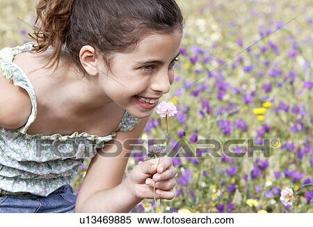 Smiling Pre-teen girl bending down, smelling flower in field of flowers View Large Photo Image Stock Photography - Smiling Pre-teen girl bending down, smelling flower in field of flowers. Fotosearch