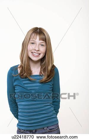 Stock Image - Smiling teenage girl, hands behind back, portrait. Fotosearch