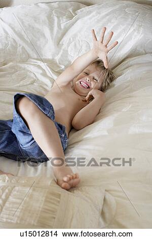 Smiling Young Boy lying in bed, Playing around View Large Photo Image Picture - Smiling Young Boy lying in bed, Playing around. Fotosearch