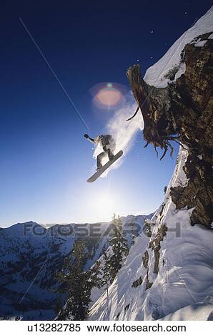 Snowboarder jumping from mountain ledge View Large Photo Image Stock Photography - Snowboarder jumping from mountain ledge. Fotosearch