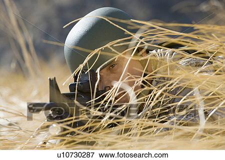 Soldier aiming rifle, hiding in long grass, (close-up) View Large Photo Image Stock Photo - Soldier aiming rifle, hiding in long grass, (close-up). Fotosearch
