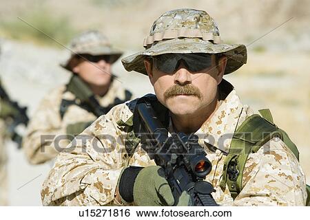 Stock Photograph - Soldier carrying rifle, outdoors. Fotosearch