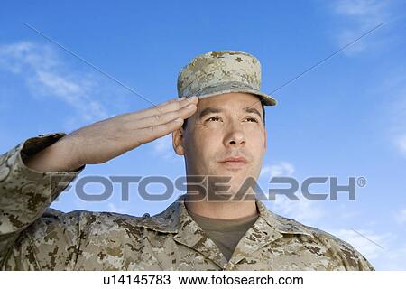 Stock Image - Soldier saluting against sky, (close-up). Fotosearch