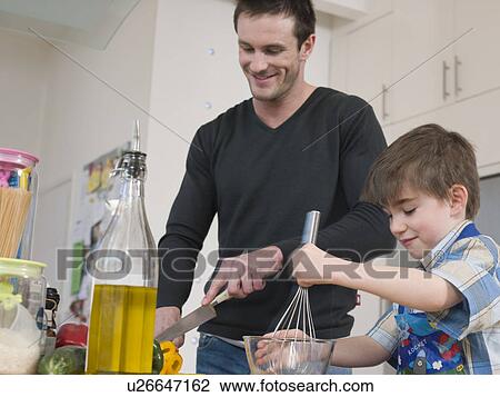 Stock Image - Son Helping Father in Kitchen. Fotosearch
