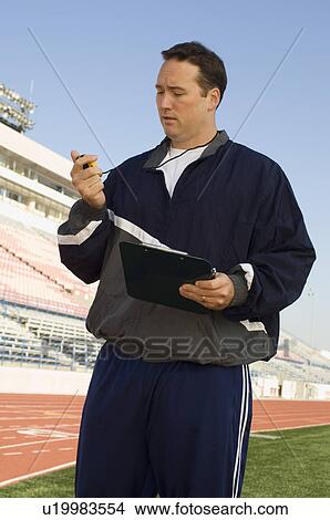 Sports coach looking at stopwatch View Large Photo Image Picture - Sports coach looking at stopwatch. Fotosearch