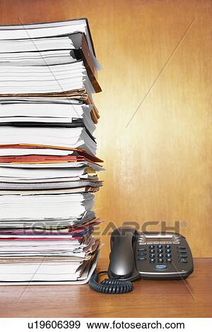 Stock Photo - Stack of paperwork and telephone on desk. Fotosearch