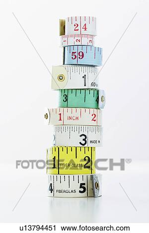 Stock Image - Stack of rolls of measuring tape, close-up. Fotosearch