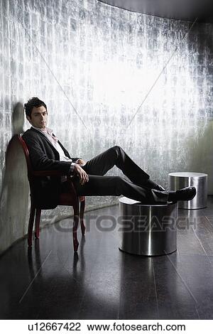 Stylish Man sitting, legs on ottoman, in metal room, side view View Large Photo Image Stock Image - Stylish Man sitting, legs on ottoman, in metal room, side view. Fotosearch