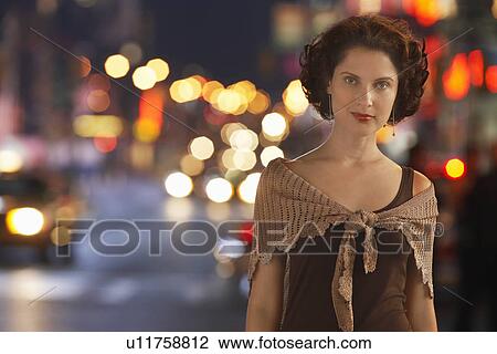 Stock Image - Stylish Woman on Sidewalk at night. Fotosearch