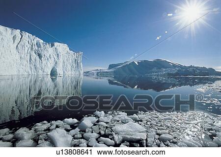 Stock Image - Sun over icebergs and ocean. Fotosearch