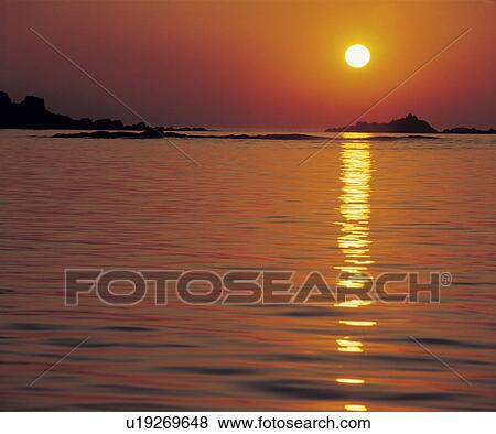 Stock Photo - Sun reflecting on water at sunset. Fotosearch