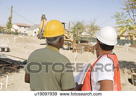 Surveyor and contraction worker at construction site, back view View Large Photo Image Stock Photo - Surveyor and contraction worker at construction site, back view. Fotosearch