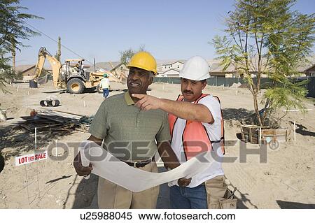 Stock Photography - Surveyor and contraction worker at construction site. Fotosearch