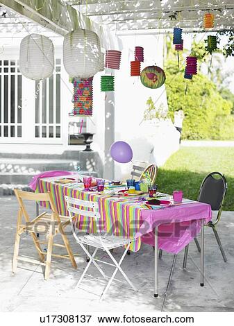 Stock Photo - Table and decorated patio after birthday party. Fotosearch