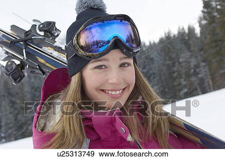 Stock Photo - Teenage girl (16-17) holding skis in snow, portrait.. Fotosearch