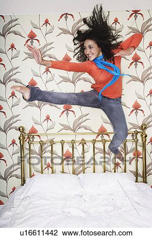 Teenage Girl, arms outspread, kicking, jumping on bed View Large Photo Image Stock Image - Teenage Girl, arms outspread, kicking, jumping on bed. Fotosearch