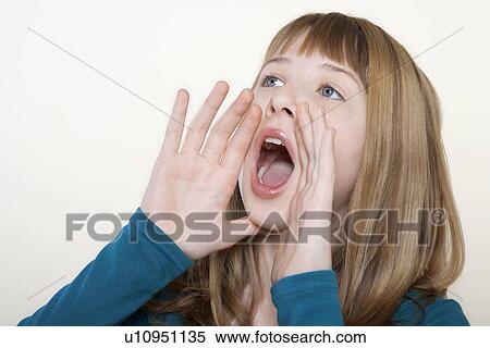 Stock Photography - Teenage girl, hands cuffed around mouth, shouting, close-up. Fotosearch