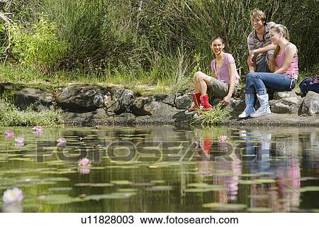 Teenage girls and boy (16-17 years) sitting on stones by lake, smiling View Large Photo Image Stock Image - Teenage girls and boy (16-17 years) sitting on stones by lake, smiling. Fotosearch