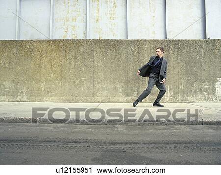 Stock Image - Teenager in suit running on street, looking back. Fotosearch