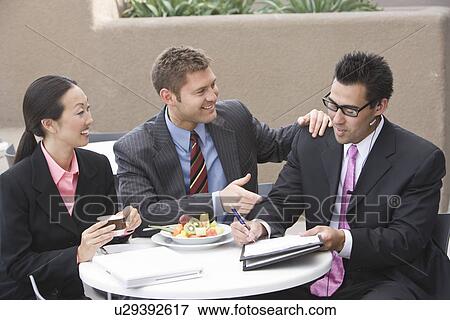 Stock Photo - Three business people having meeting at lunch. Fotosearch