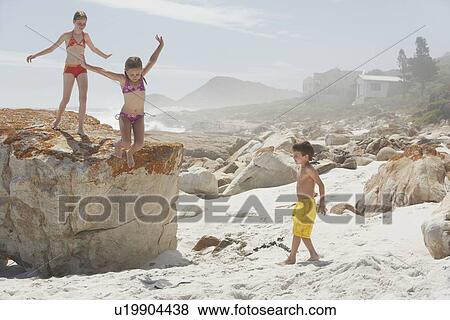 Stock Photo - Three Children Playing on Rocky Beach. Fotosearch