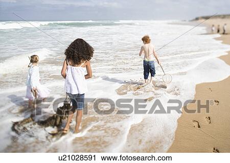 Stock Image - Three children walking on beach. Fotosearch