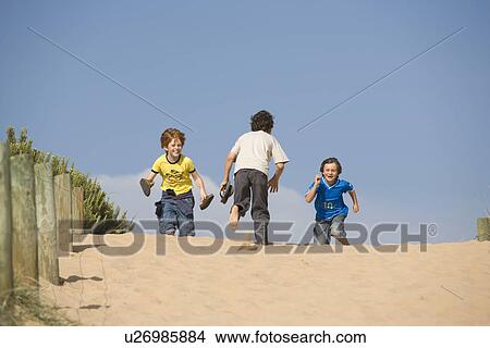 Three pre-teen boys running towards beach View Large Photo Image Picture - Three pre-teen boys running towards beach. Fotosearch