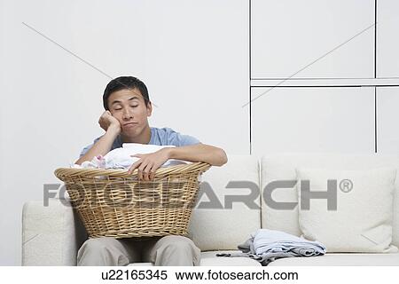 Tired Man resting head in hand on full Laundry basket, sitting on Sofa View Large Photo Image Stock Photography - Tired Man resting head in hand on full Laundry basket, sitting on Sofa. Fotosearch