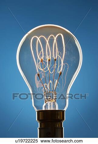 Stock Photography - Transparent light bulb against blue background in studio. Fotosearch