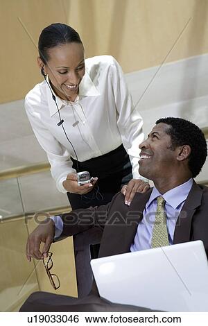 Stock Photograph - Two business colleagues using laptop and mobile phone. Fotosearch