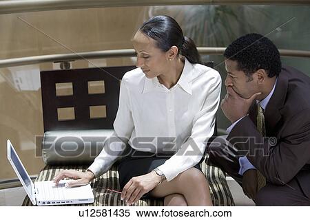 Stock Photography - Two business people working on laptop. Fotosearch