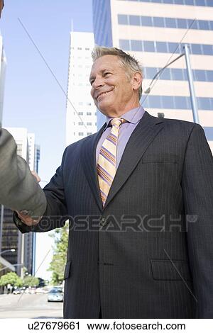 Two businessmen shaking hands, outdoors View Large Photo Image Stock Image - Two businessmen shaking hands, outdoors. Fotosearch