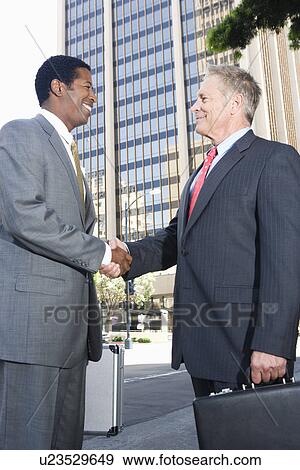 Two businessmen shaking hands, outdoors View Large Photo Image Stock Photo - Two businessmen shaking hands, outdoors. Fotosearch