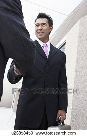 Two Businessmen Shaking Hands outside office, low angle view View Large Photo Image Stock Photo - Two Businessmen Shaking Hands outside office, low angle view. Fotosearch