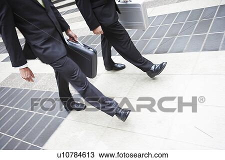 Two businessmen walking with briefcases, low section View Large Photo Image Stock Image - Two businessmen walking with briefcases, low section. Fotosearch