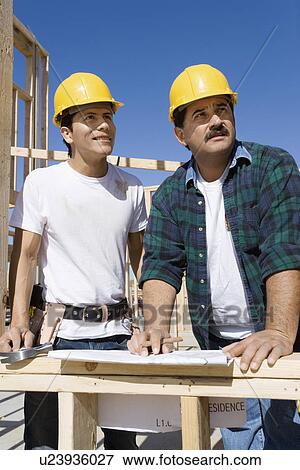 Two construction workers looking up, on construction site View Large Photo Image Stock Photo - Two construction workers looking up, on construction site. Fotosearch