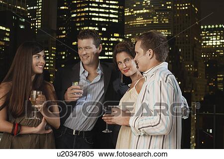 Two couples drinking together against night city skyline View Large Photo Image Stock Photography - Two couples drinking together against night city skyline. Fotosearch